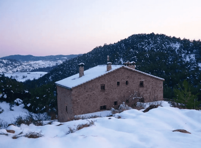 Una casa está situada en la cima de una colina cubierta de nieve.