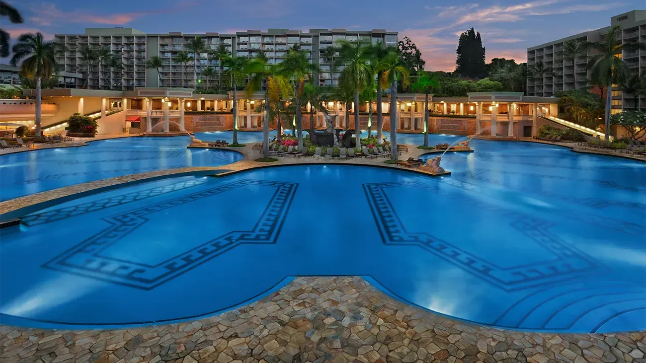 A large swimming pool in front of a hotel at night