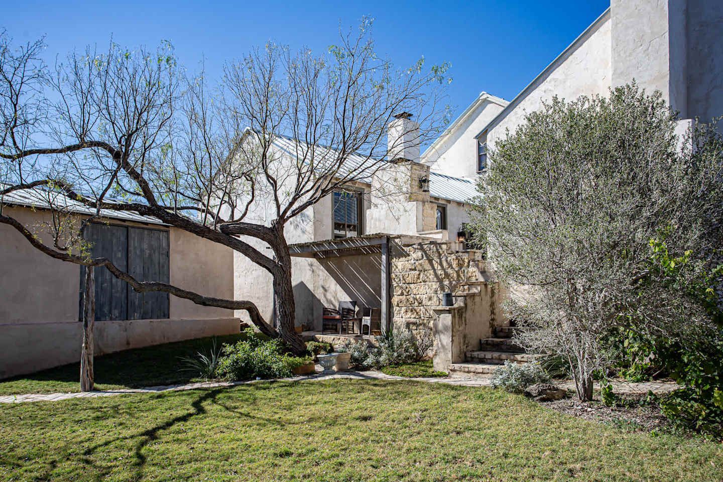 A small house is sitting on top of a lush green hill surrounded by trees.