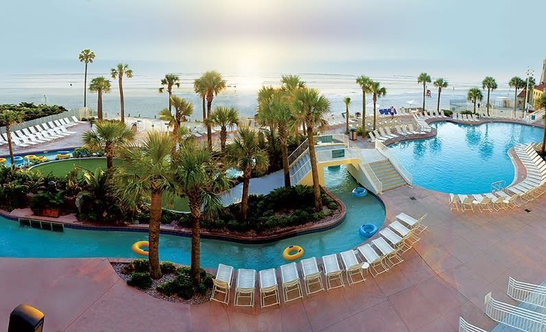 A large swimming pool surrounded by palm trees at night