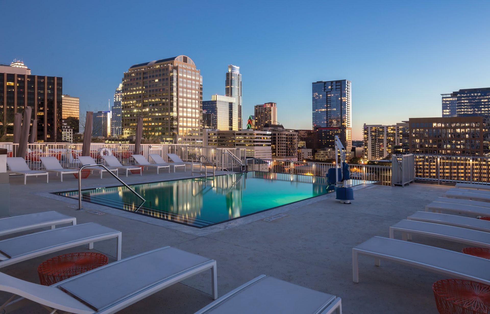 There is a swimming pool on the roof of a building with a city in the background.