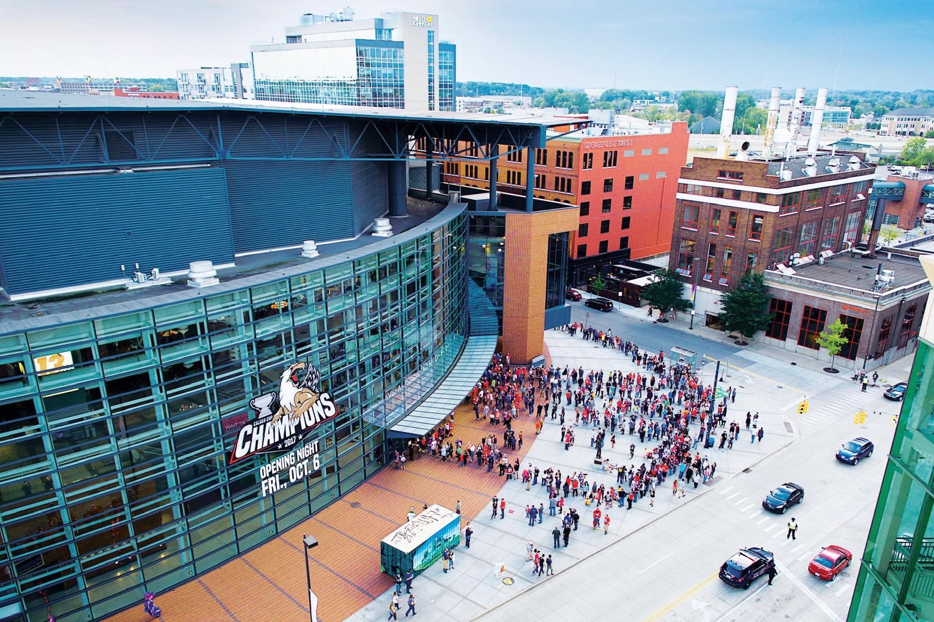 An aerial view of a large building with a lot of people in front of it