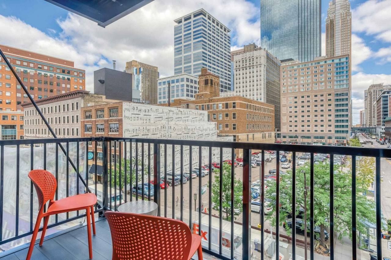 A balcony with two chairs and a table overlooking a city.