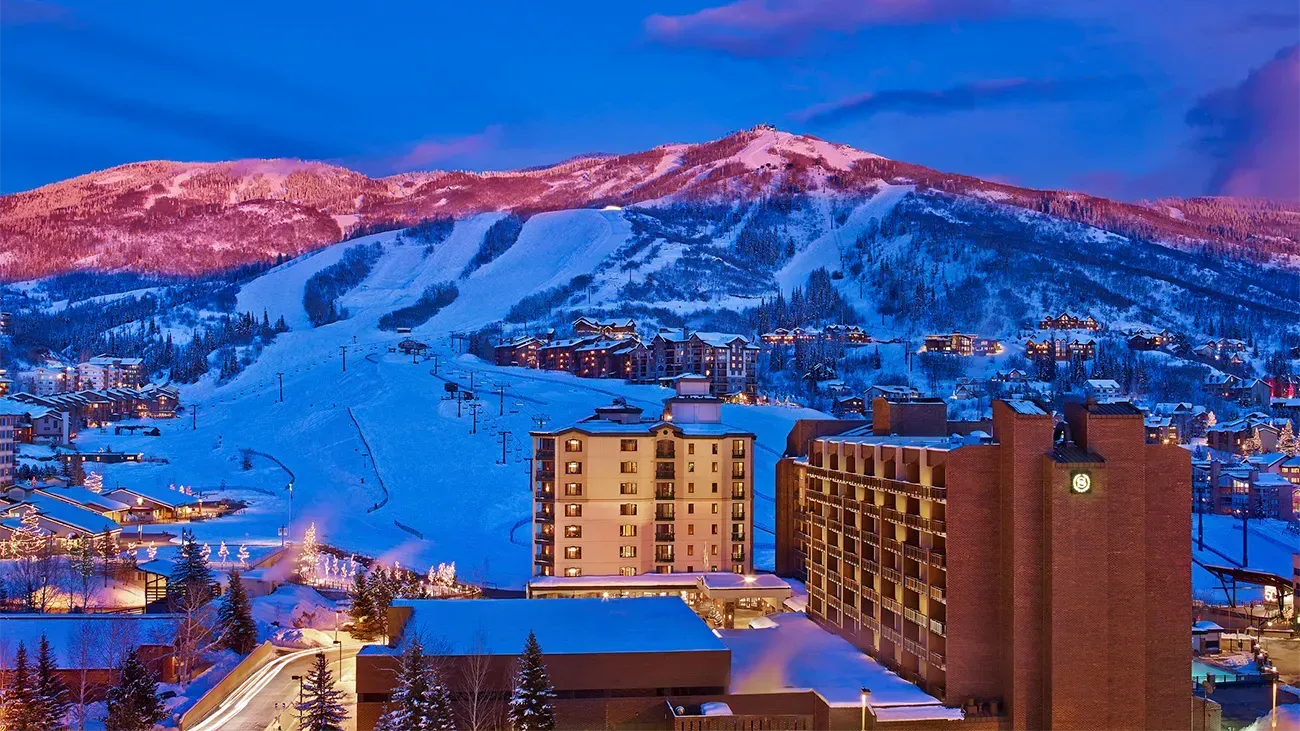 An aerial view of a ski resort at night with a mountain in the background.