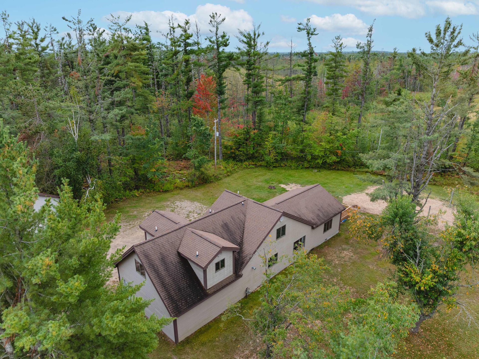 House with brown roof surrounded by trees and green grass.