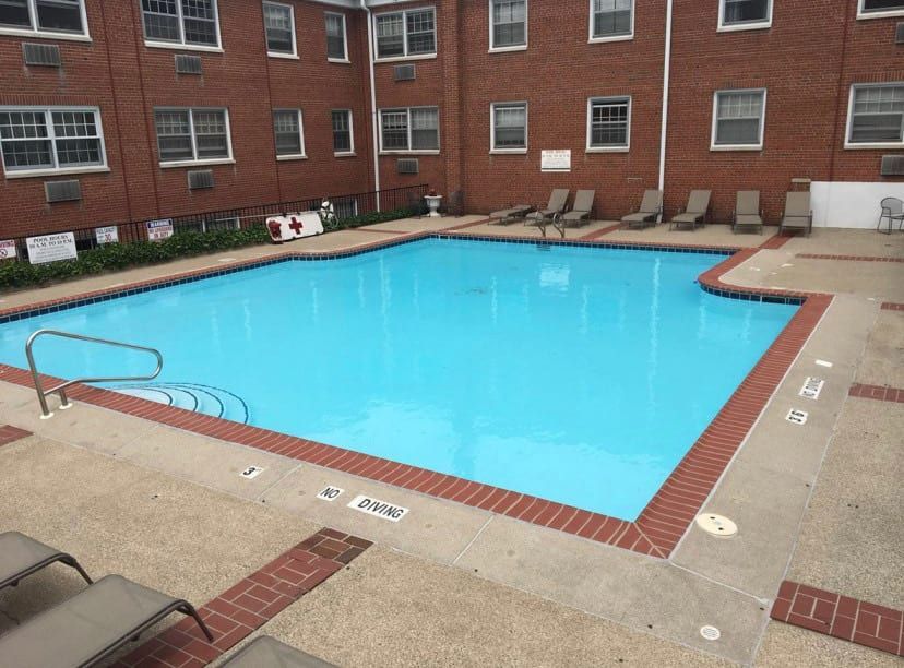 A large swimming pool in front of a brick building
