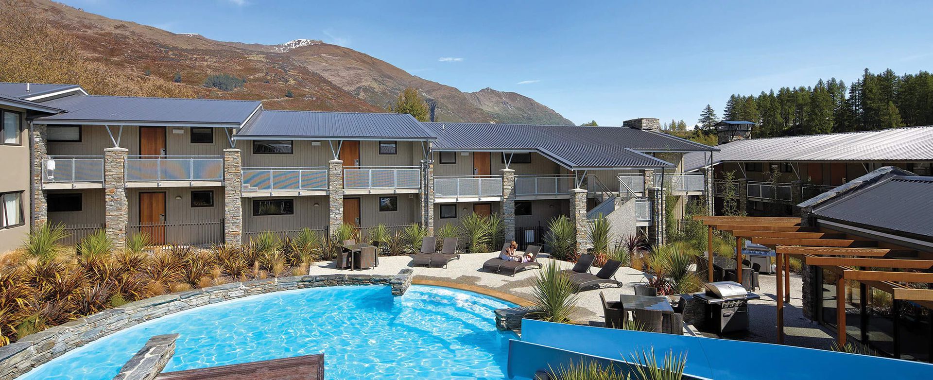 A large swimming pool in front of a hotel with mountains in the background