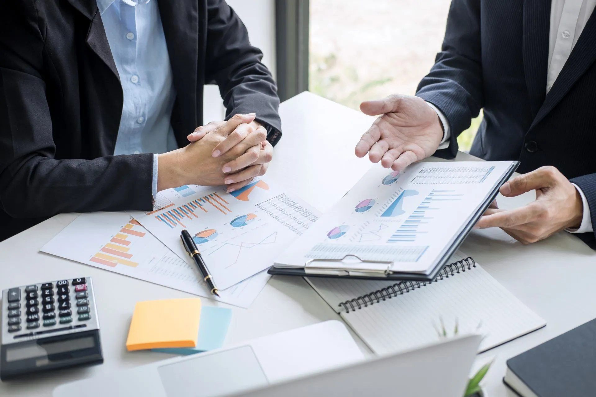 Ein Mann und eine Frau sitzen an einem Tisch und schauen auf ein Klemmbrett. Oliver Weiler - Finanzcoach