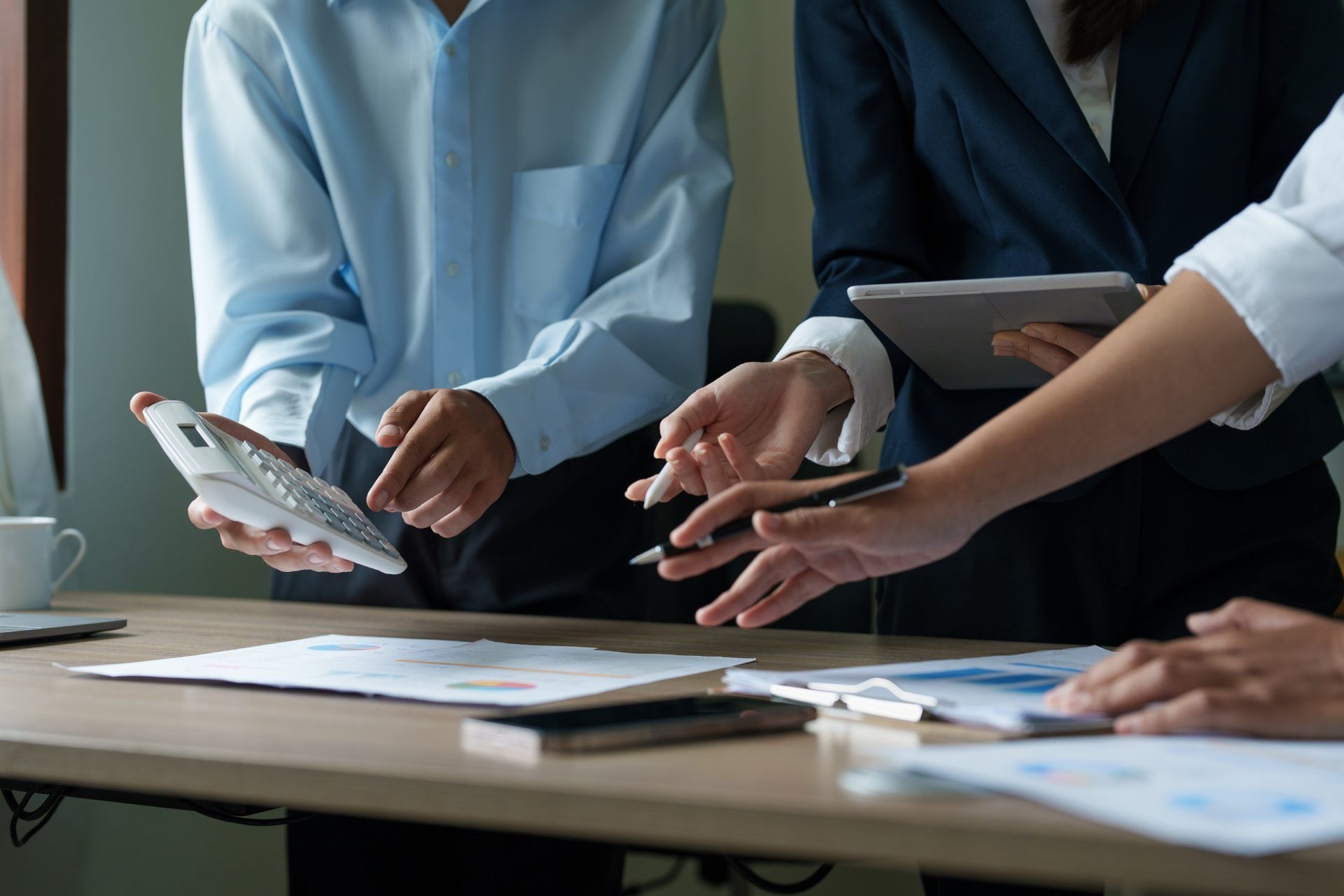 Eine Gruppe von Leuten sitzt um einen Tisch herum und schaut auf einen Taschenrechner. Oliver Weiler - Finanzcoach