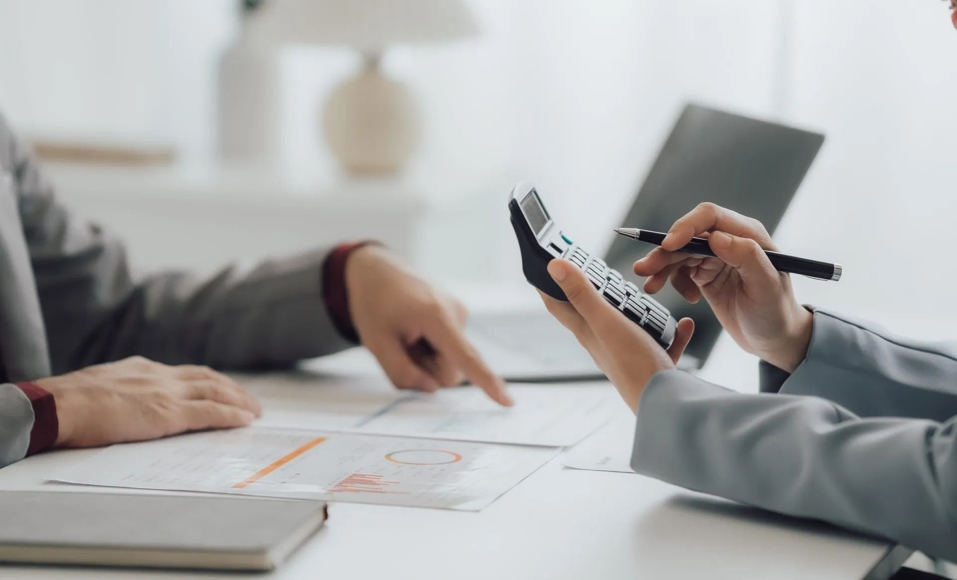 Eine Gruppe von Leuten sitzt um einen Tisch herum und schaut auf einen Taschenrechner. Oliver Weiler - Finanzcoach, Oliver Weiler - Finanzcoach