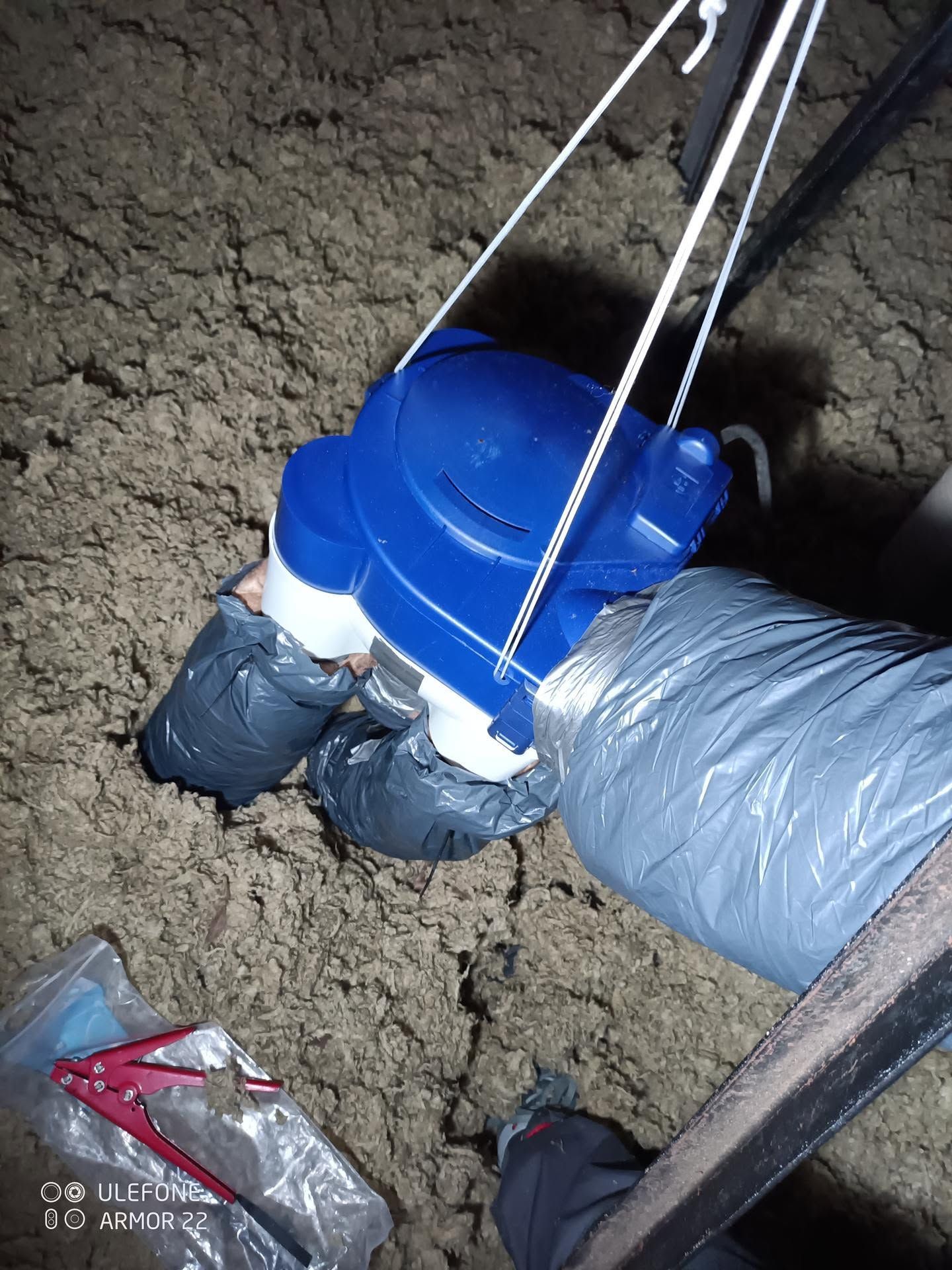 Installation bleue et grise descendue dans une tranchée boueuse à l’aide de cordes