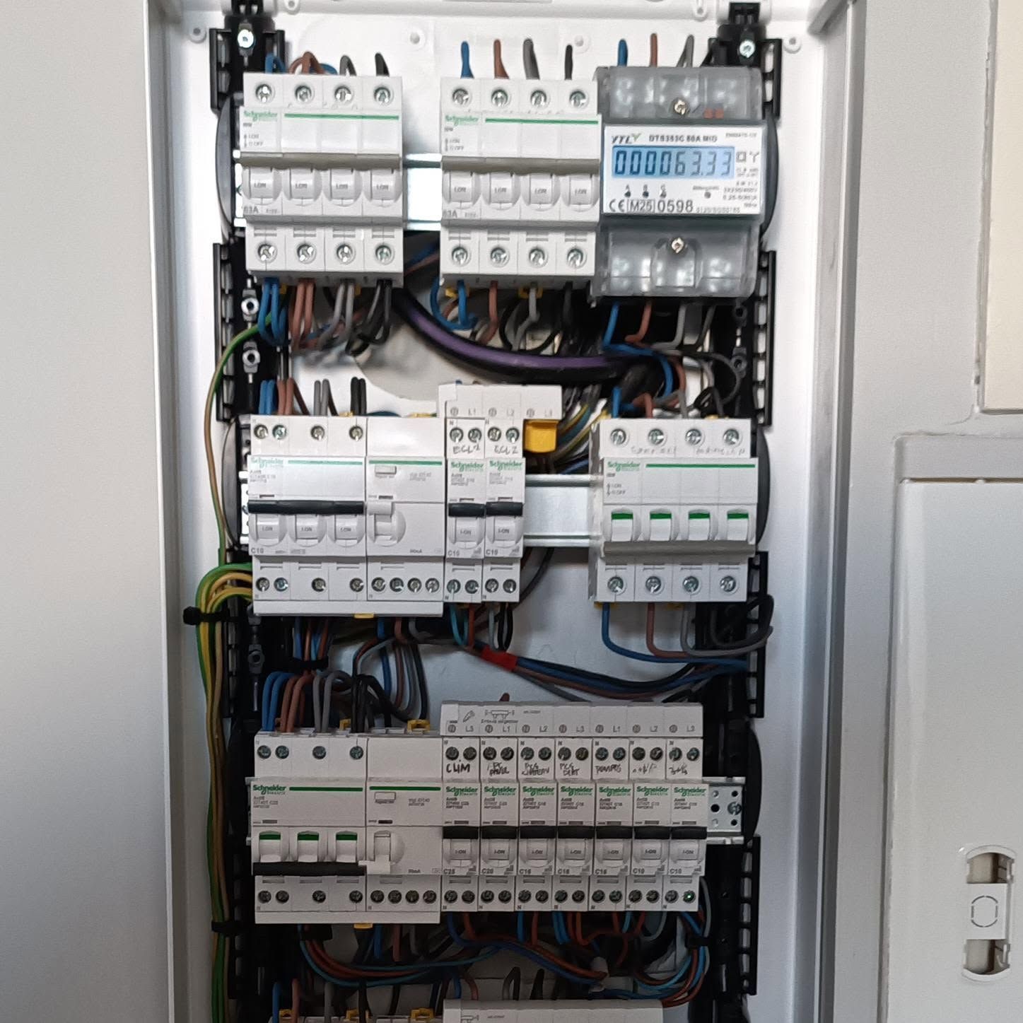 Panneau électrique ouvert avec des rangées de disjoncteurs et des fils électriques