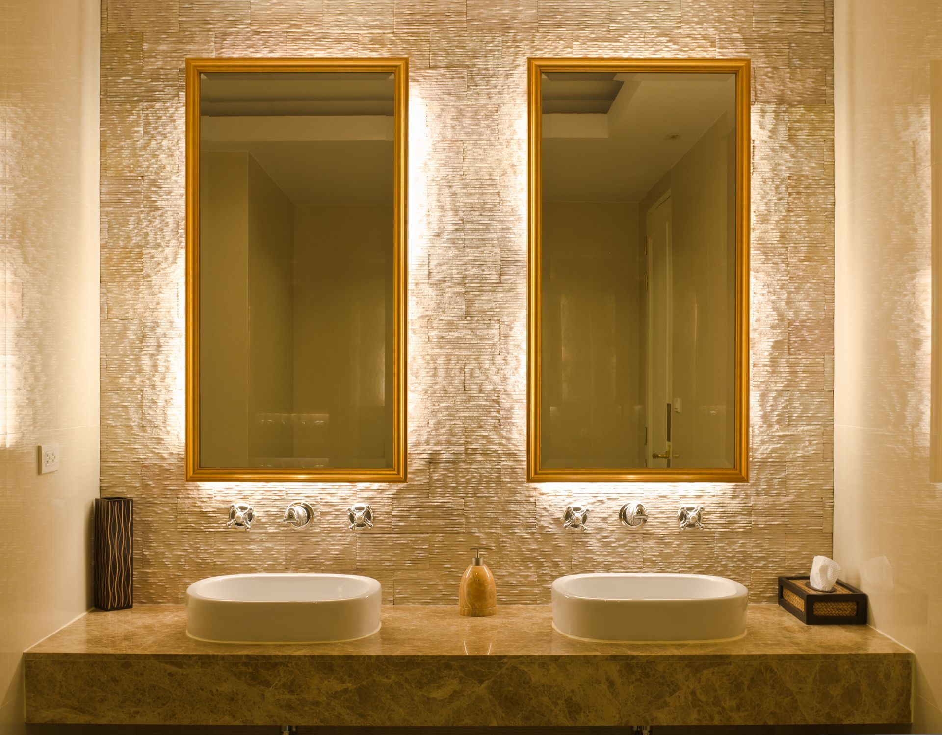Élégant meuble-lavabo de salle de bains avec deux vasques rondes, des miroirs à cadre doré et un éclairage chaleureux aux textures douces.