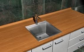 Un fregadero de acero inoxidable está sobre una encimera de madera en una cocina.