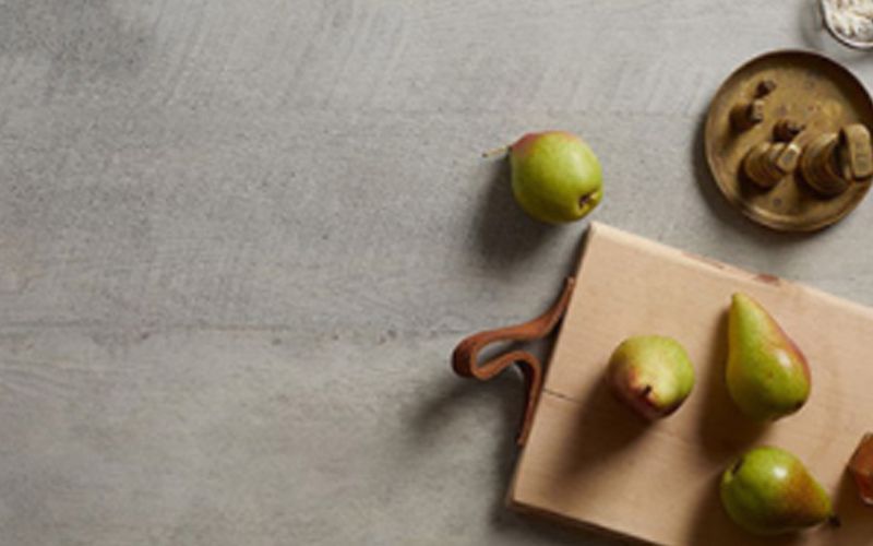 Una tabla de cortar con peras y manzanas sobre una mesa.