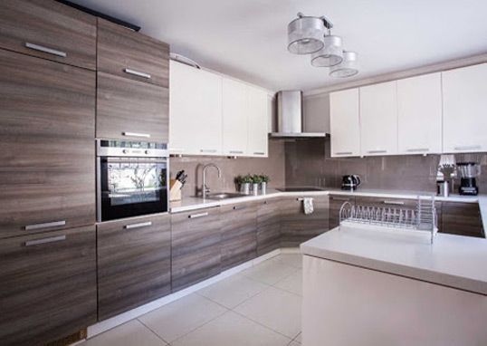Una cocina con gabinetes de madera y encimeras blancas.