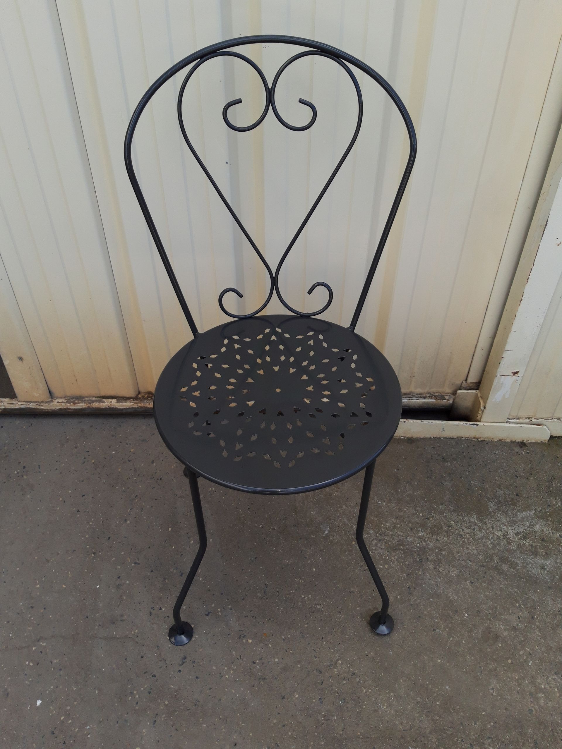 Chaise de jardin en métal qui a bénéficié d'un décapage et qui arbore une peinture noire reluisante