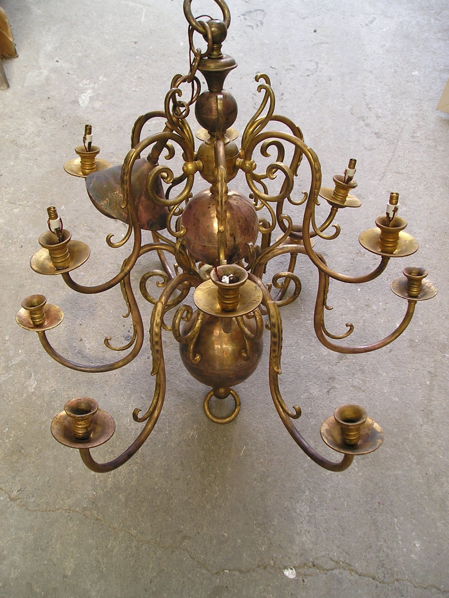 Lustre ancien en laiton orné, muni de plusieurs bougeoirs, suspendu au plafond.