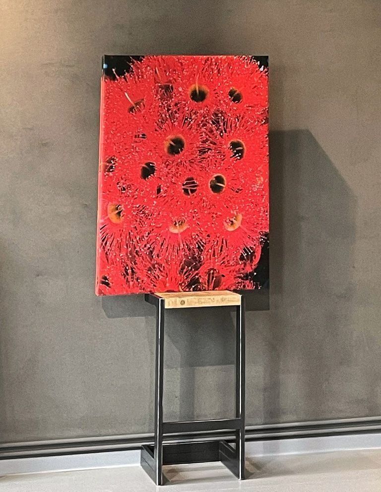 An einer Wand hängt ein großes rot-schwarzes Gemälde.