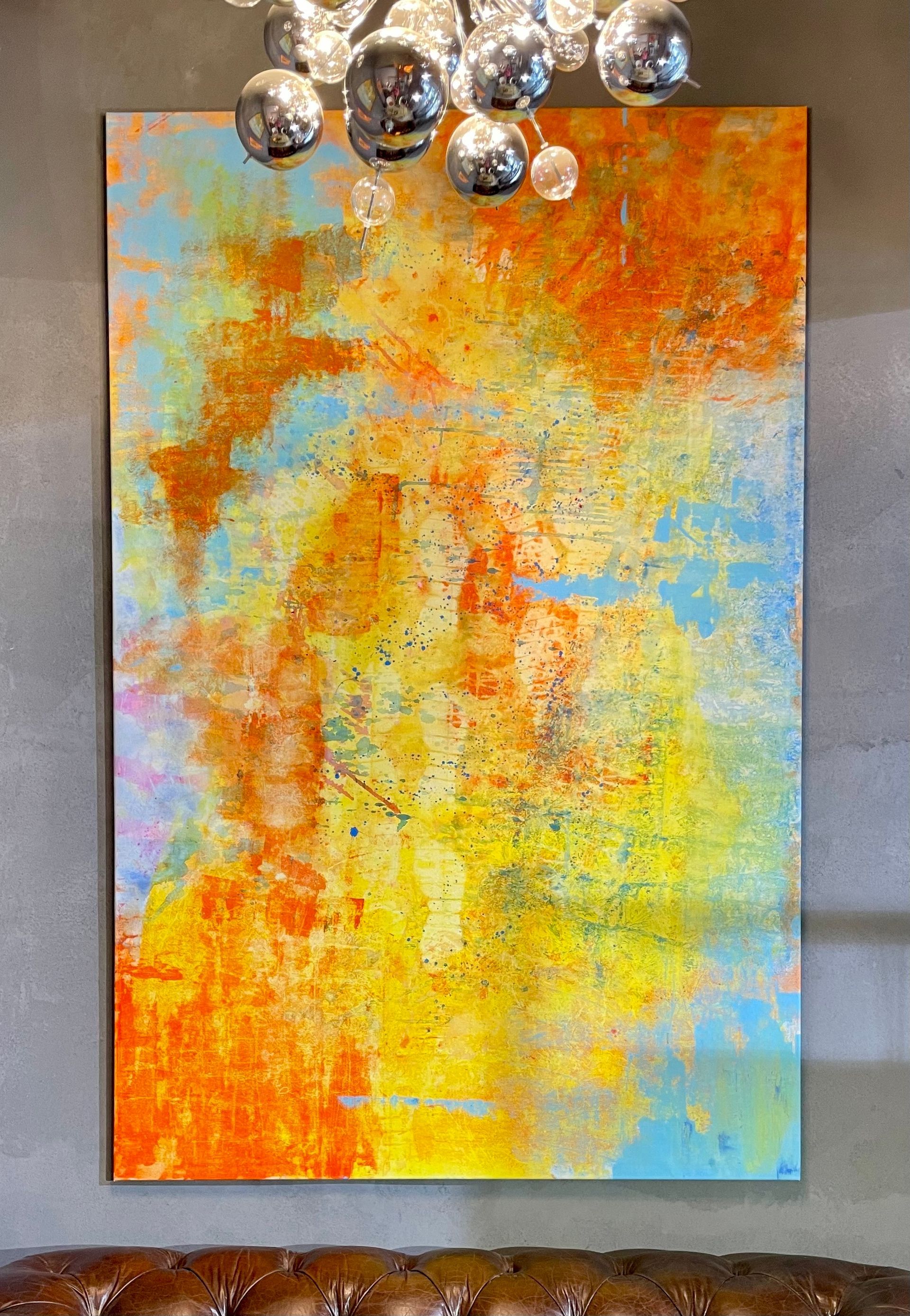 Abstrakte Kunst in Orange-, Gelb- und Blautönen auf einer großen Leinwand, an einer grauen Wand befestigt.