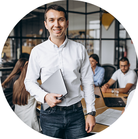 Um homem de camisa branca está segurando um laptop na frente de um grupo de pessoas.