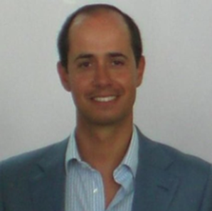 Um homem de terno e camisa listrada sorri para a câmera