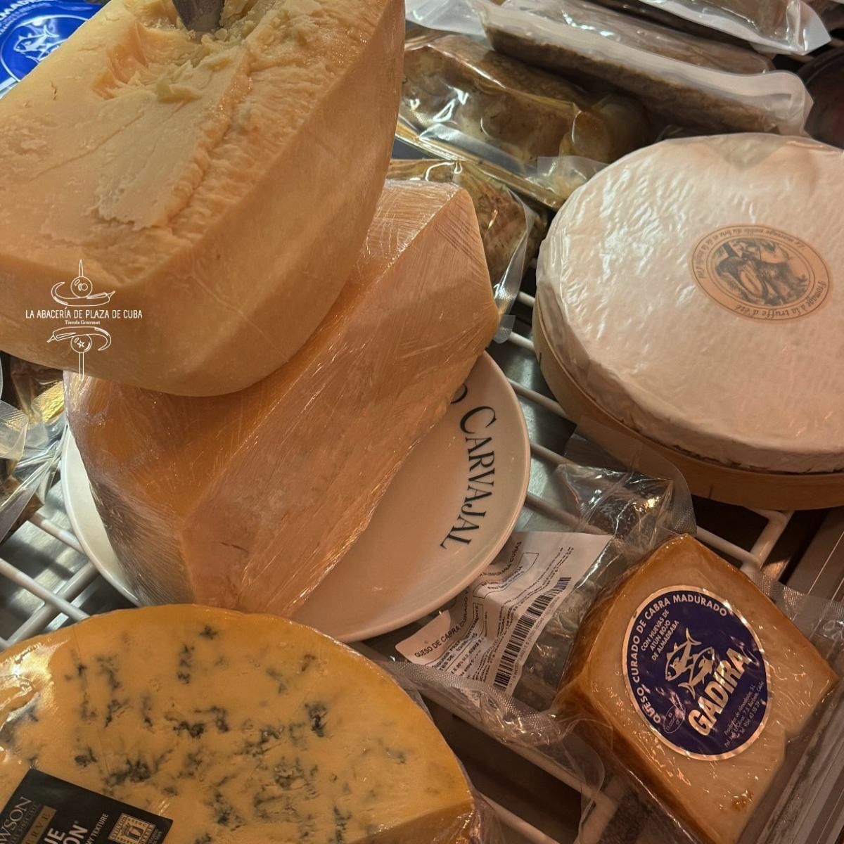 Varios quesos envueltos, incluido un queso azul y una rodaja de Brie, en un estante.