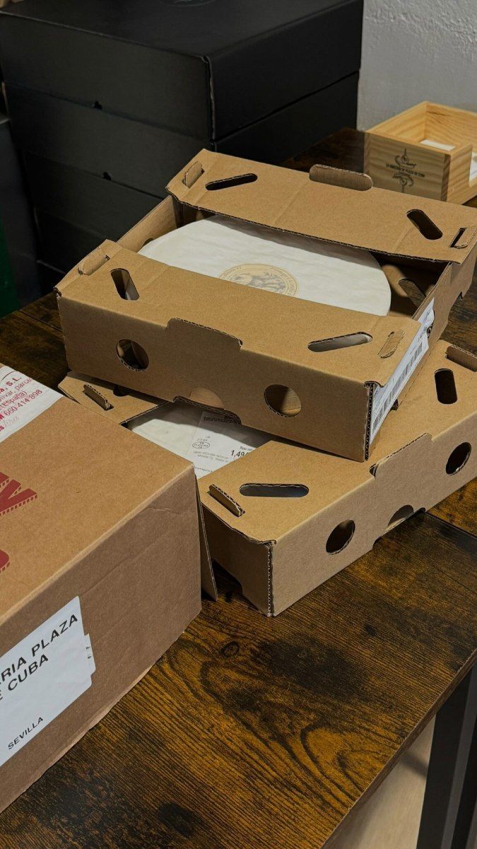 Cajas apiladas sobre una mesa de madera, algunas abiertas para revelar su contenido blanco.