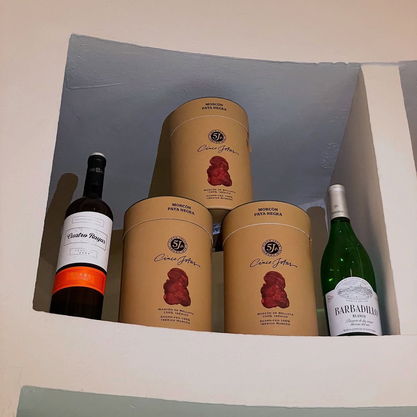 Botellas de vino y cajas de regalo redondas en un estante empotrado.
