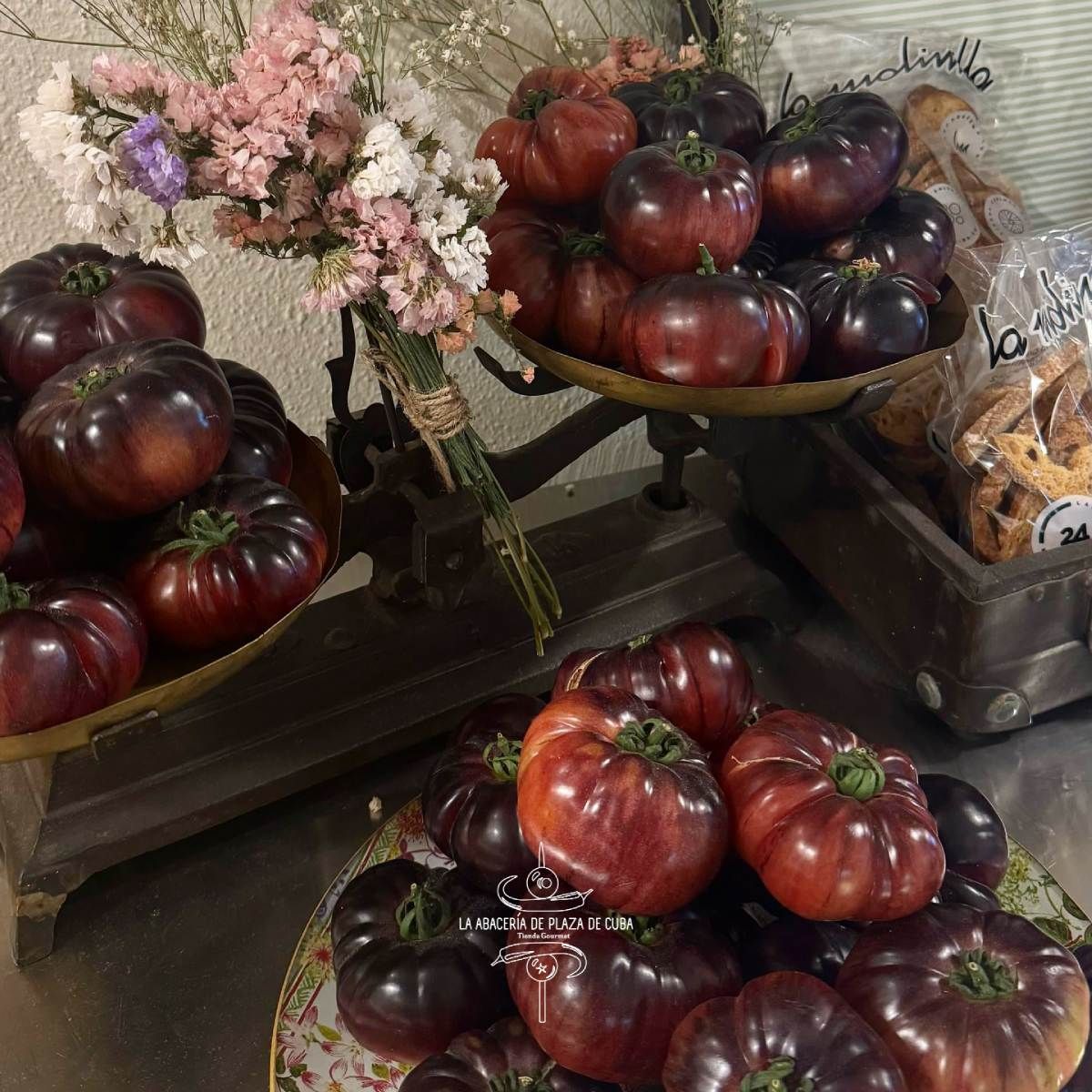 Tomates reliquia en escamas con flores y productos horneados en un entorno rústico.