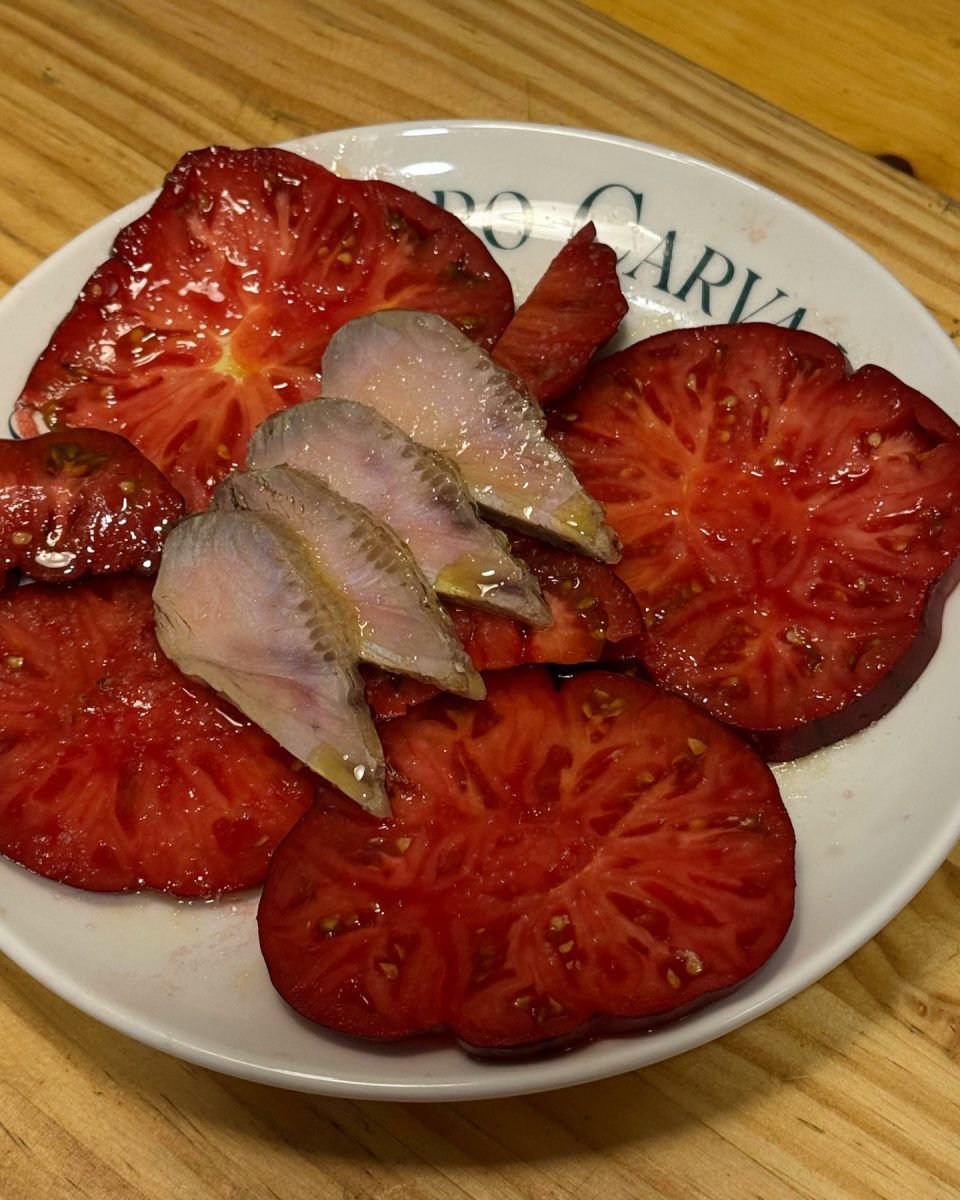 Rodajas de tomate y filetes de pescado en un plato blanco.
