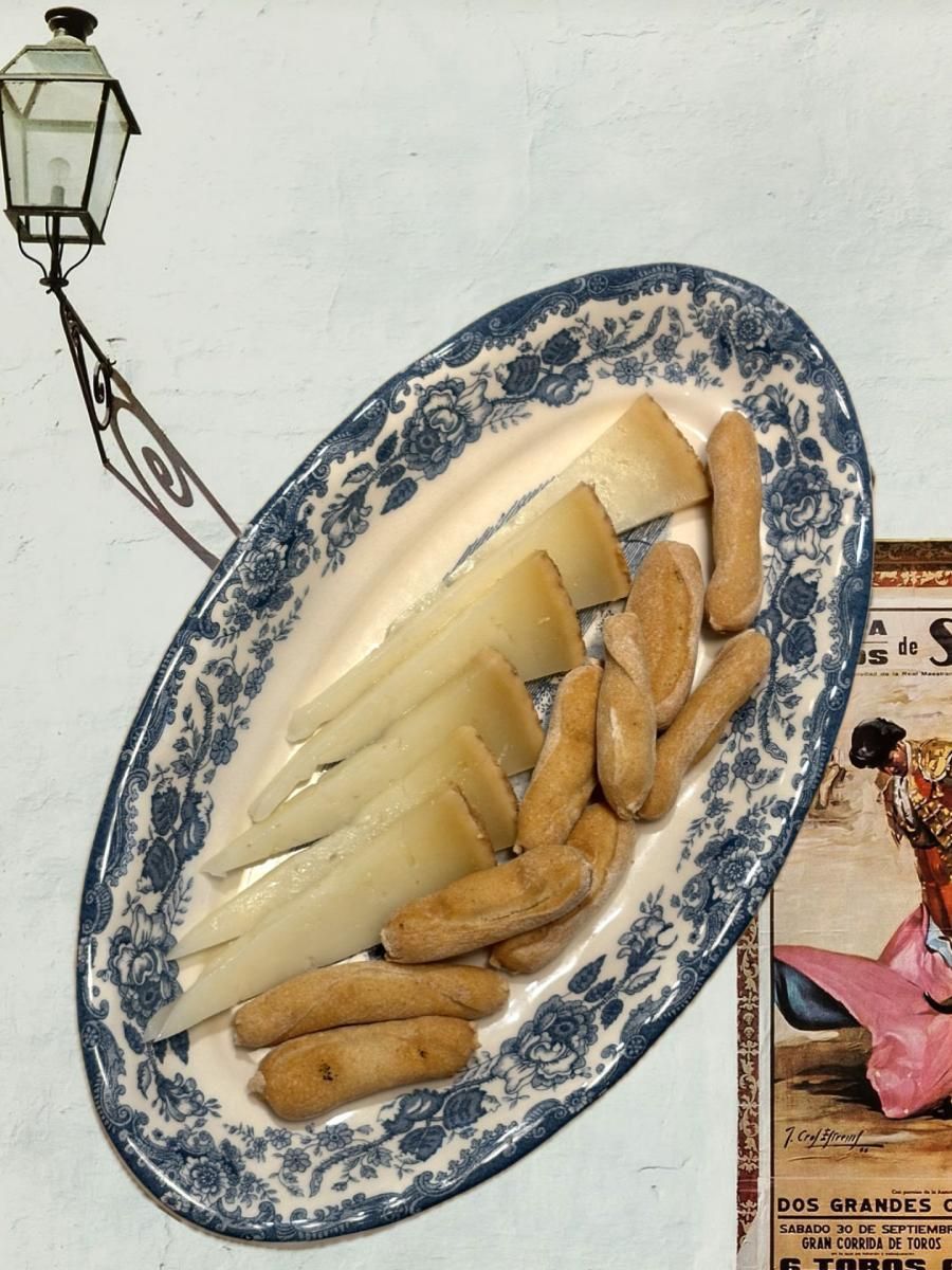 Plato ovalado con queso en lonchas y palitos de pan, estampado floral azul.