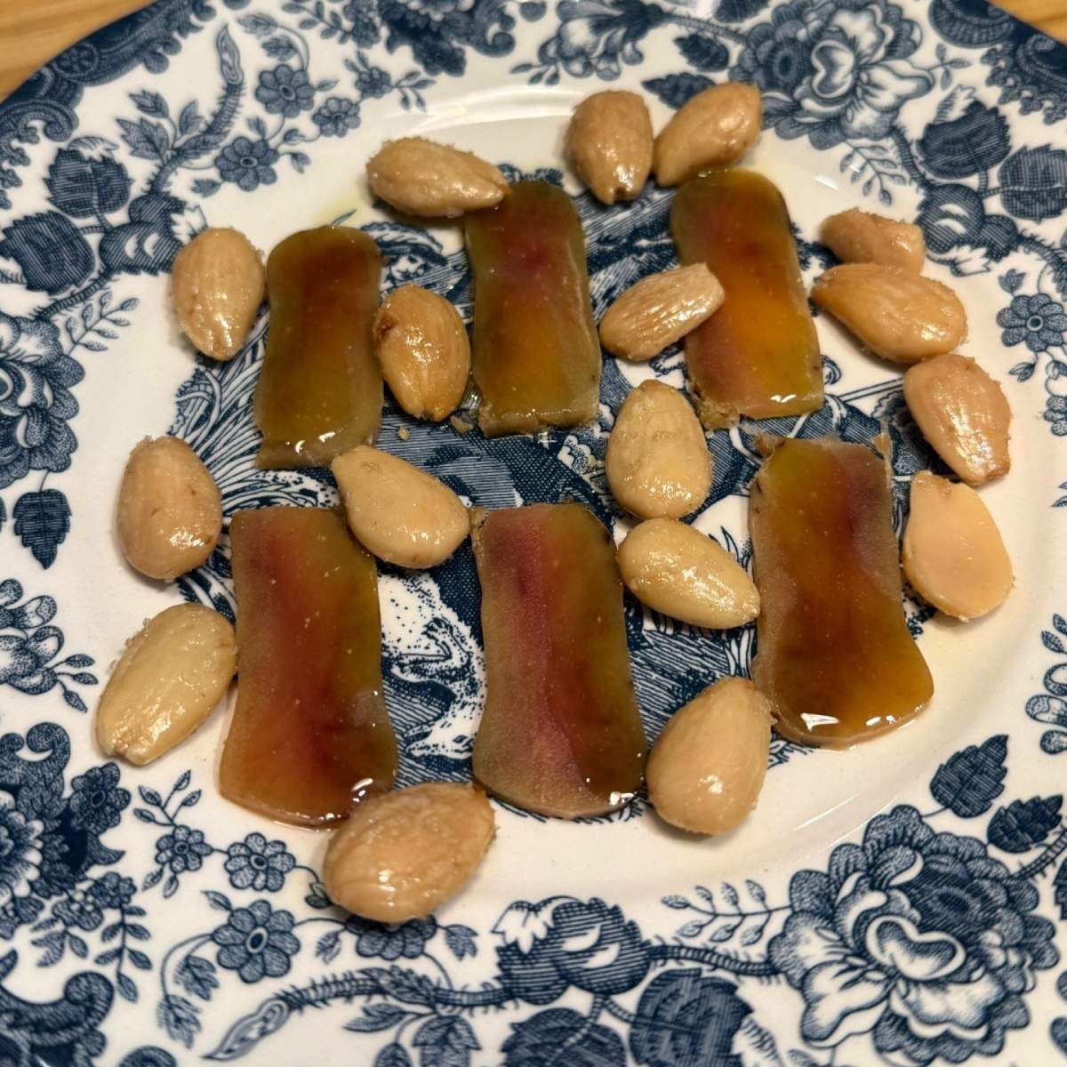 Rebanadas de pescado en conserva con almendras sobre un plato floral azul.