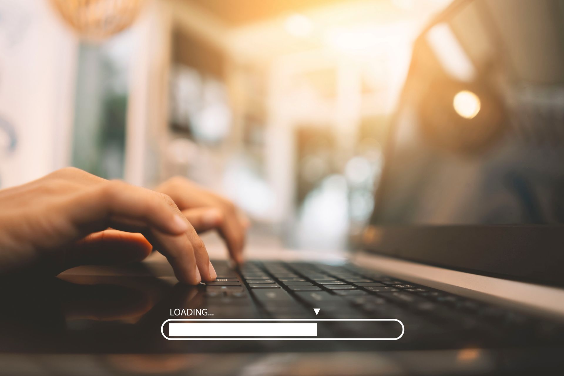 Eine Person tippt auf einem Laptop, auf dem ein Ladebalken angezeigt wird.