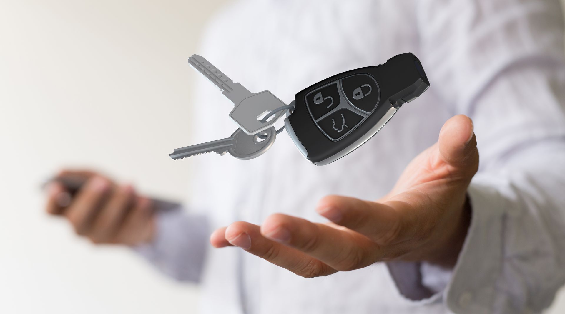 Main tenant un porte-clés de voiture avec deux clés métalliques flottant au-dessus.