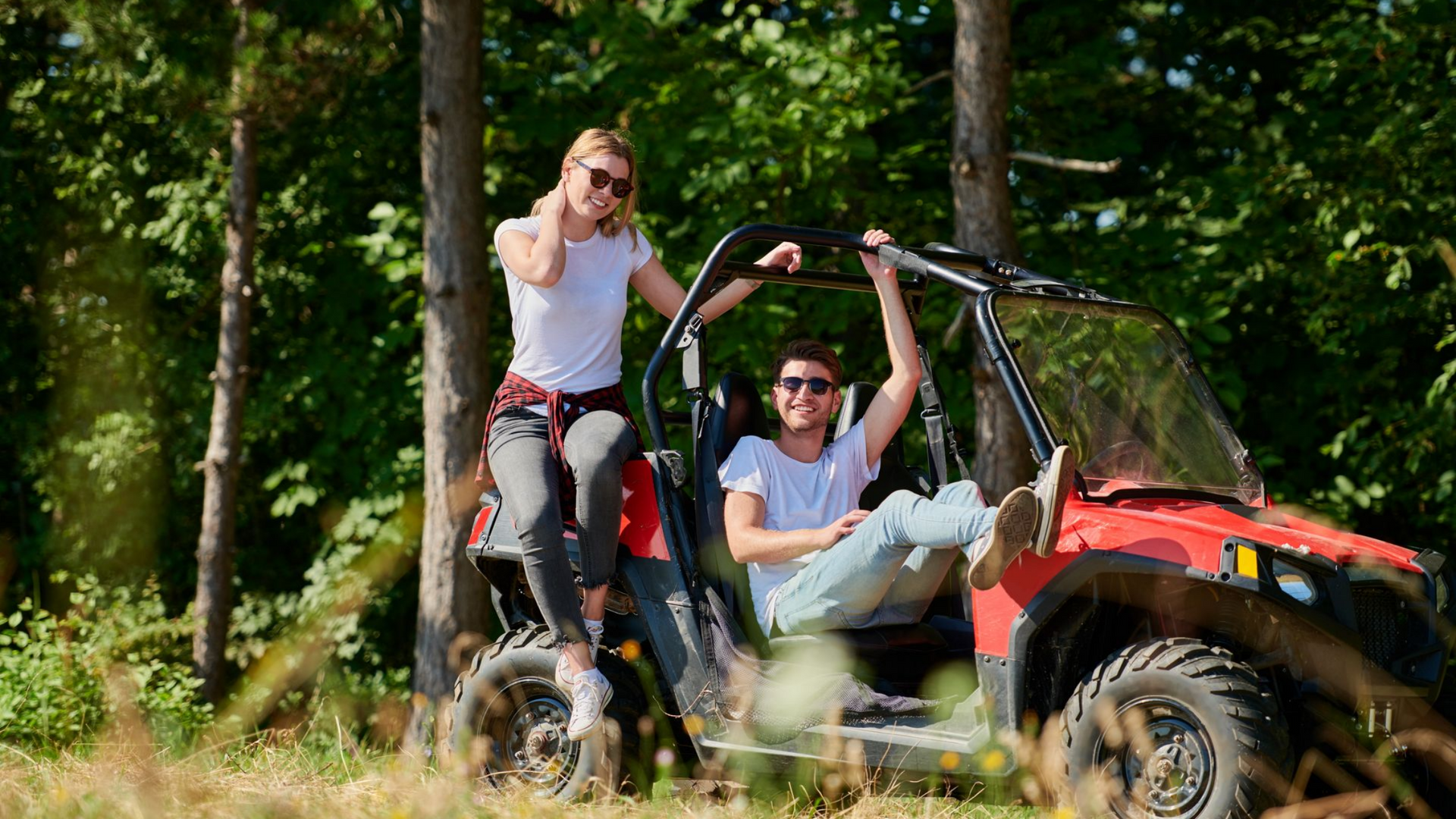 Un couple assis dans un buggy rouge à l'arrêt dans un champ.