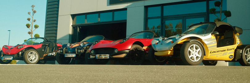 Trois buggys colorés garés devant un bâtiment moderne en verre