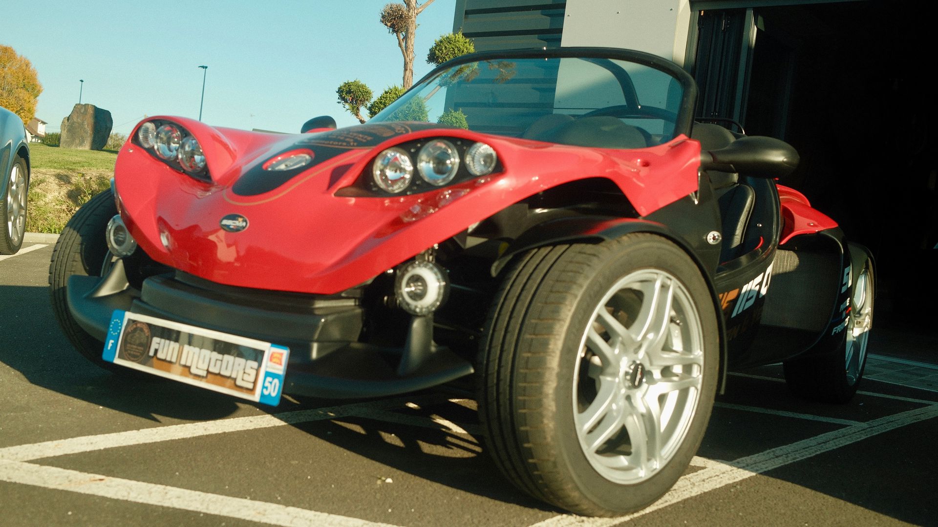 Un buggy rouge et noir garé devant le garage FUN MOTORS.