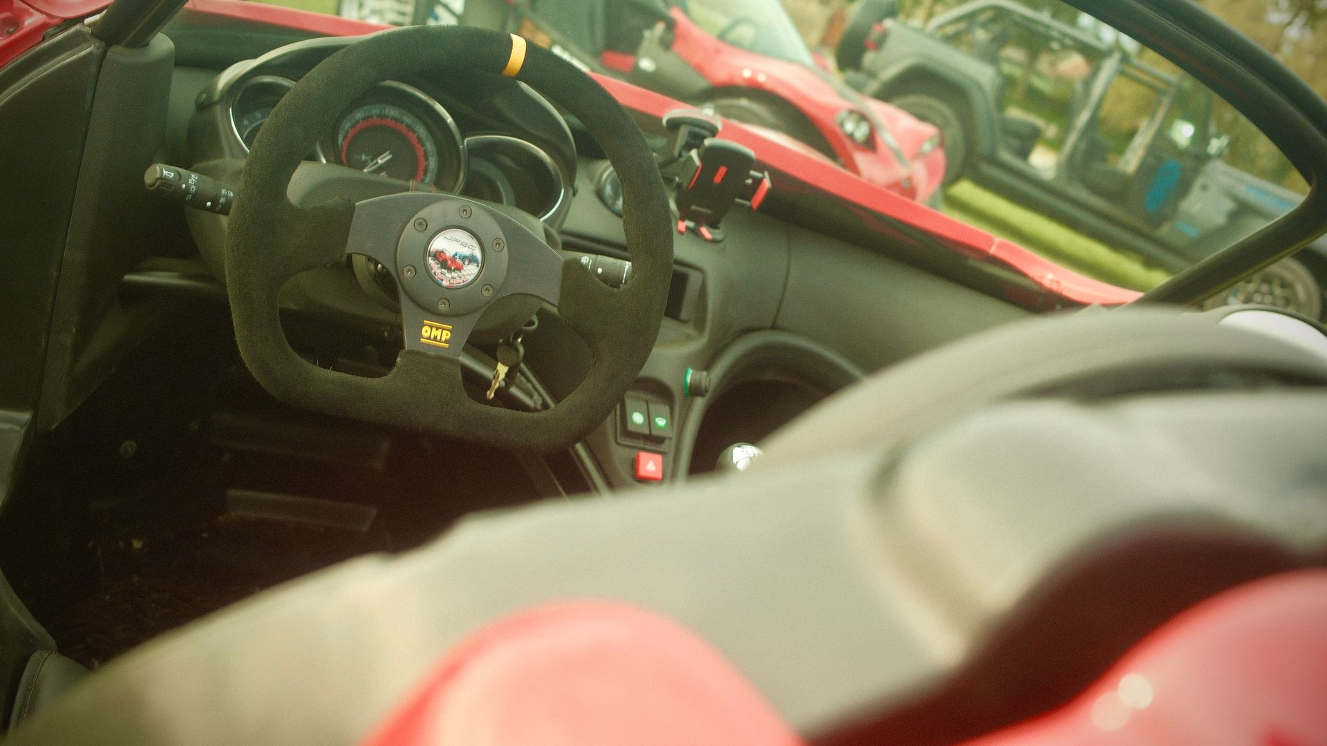 Vue intérieure d'un buggy avec volant, cadrans et tableau de bord noirs.