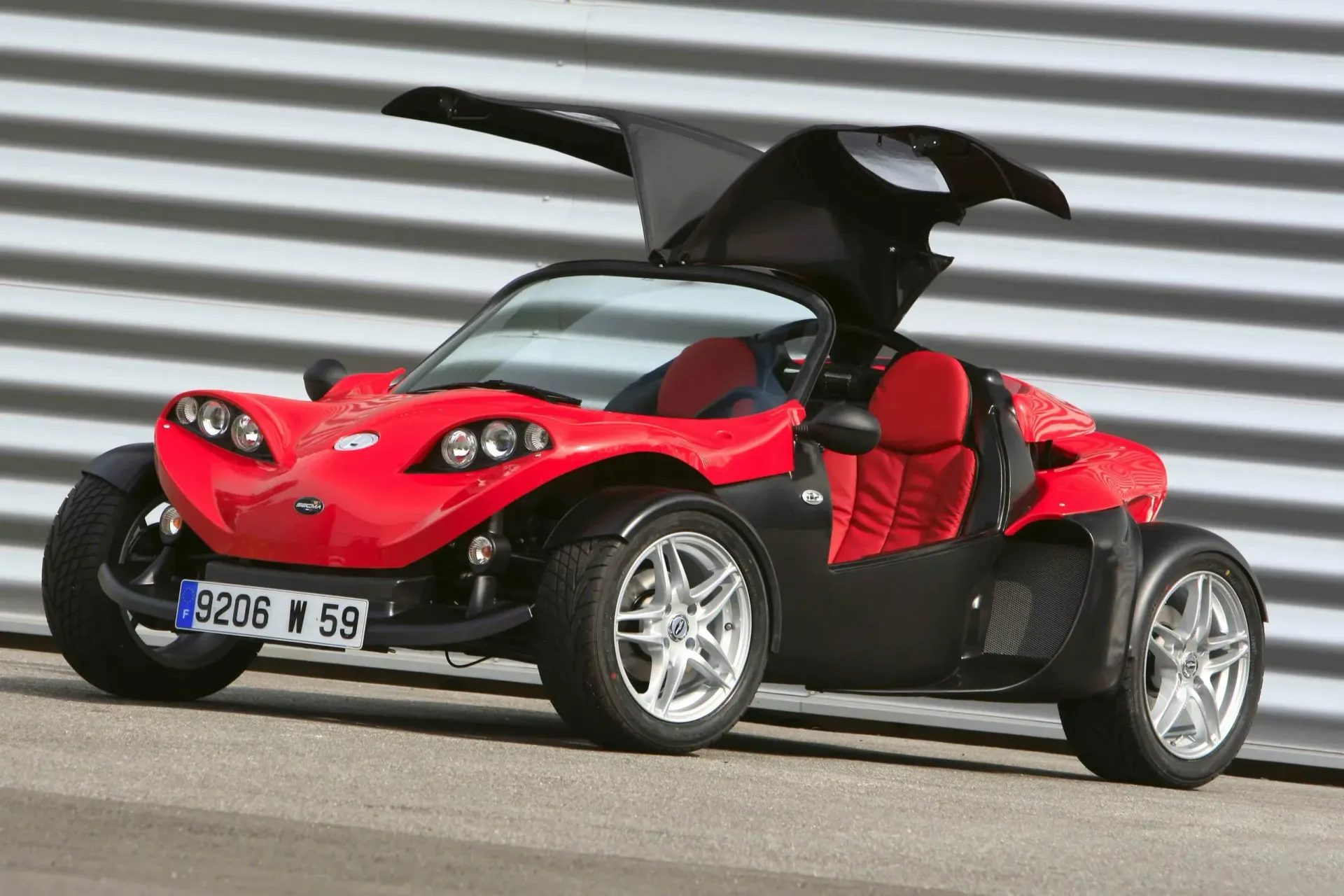 Buggy rouge à portes papillon sur une route, vue de profil