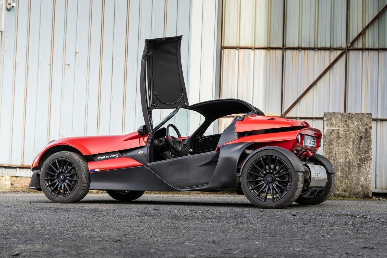 Un couple assis dans un buggy rouge à l'arrêt dans un champ.