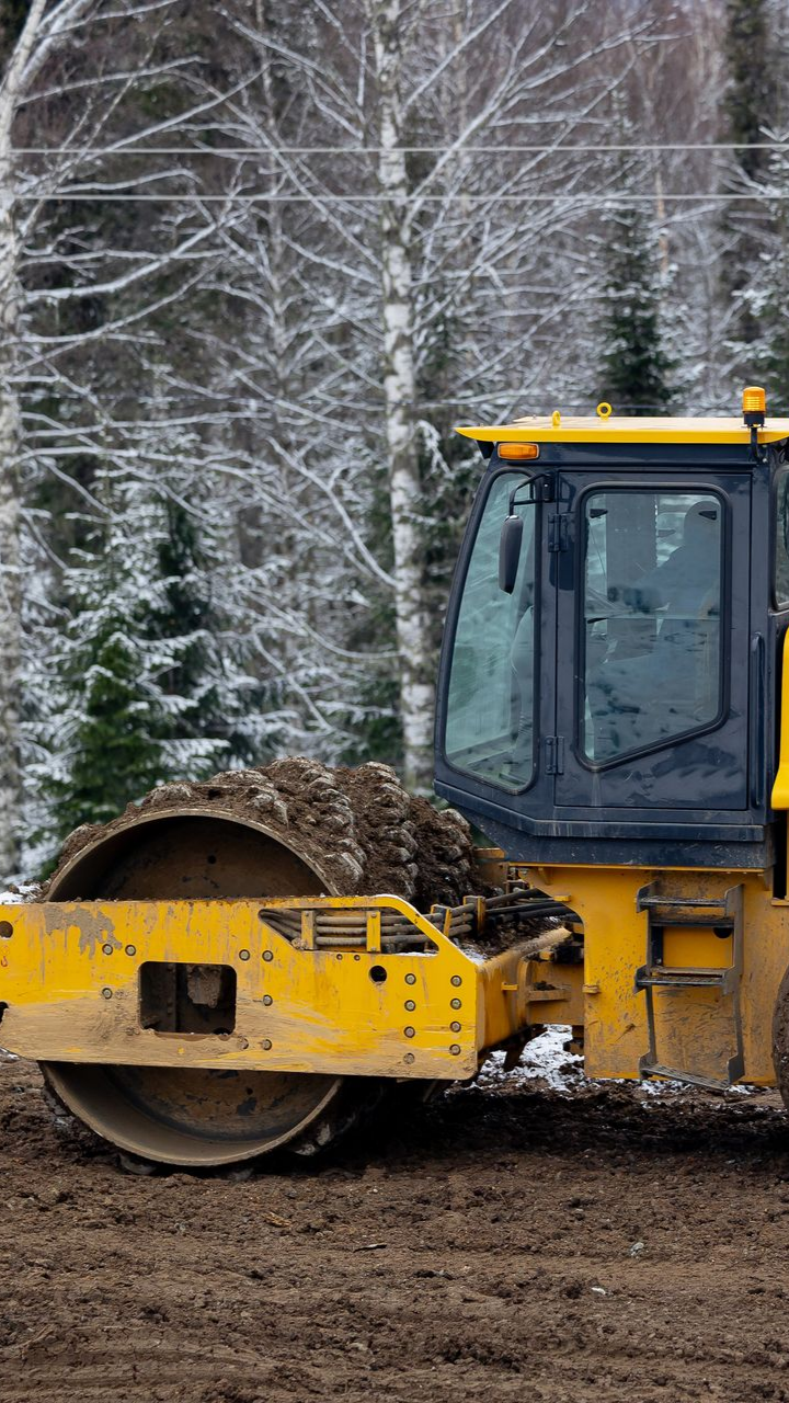 Un rouleau compresseur jaune compacte la terre 