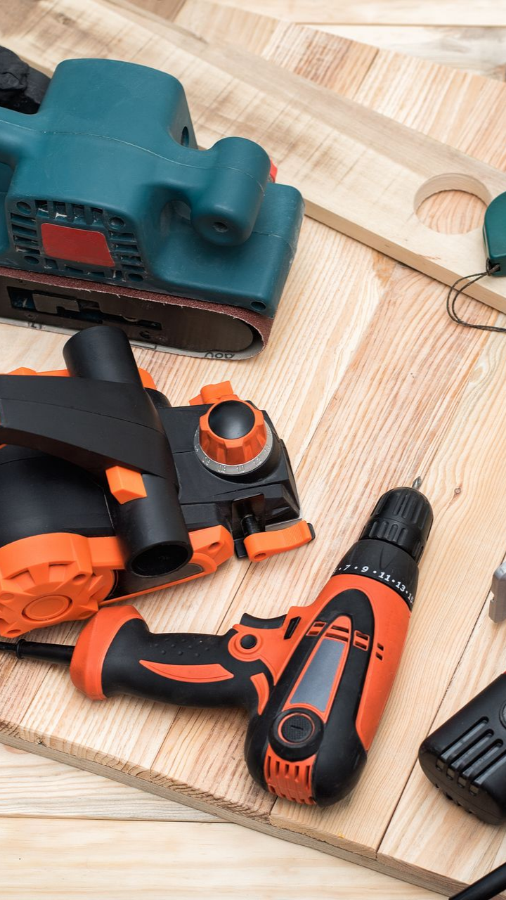 Outils électriques (ponceuse, raboteuse, perceuse) sur une surface en bois