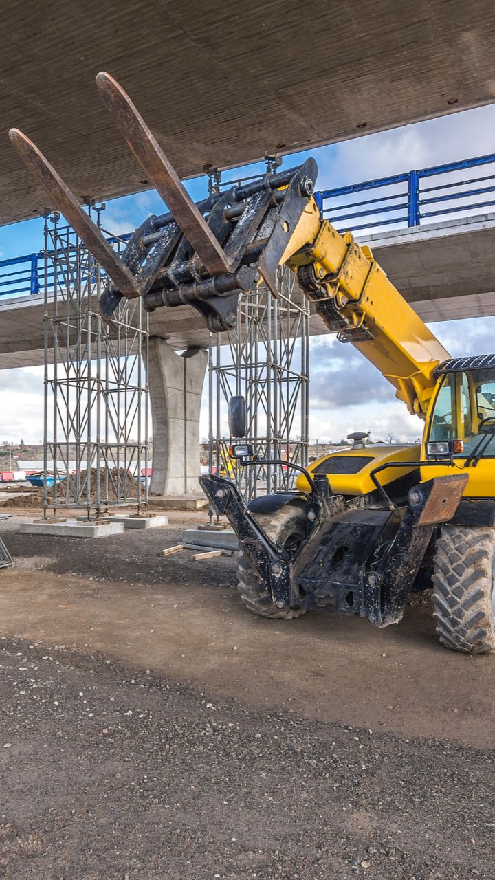 Chariot télescopique jaune à fourches levées sur un chantier