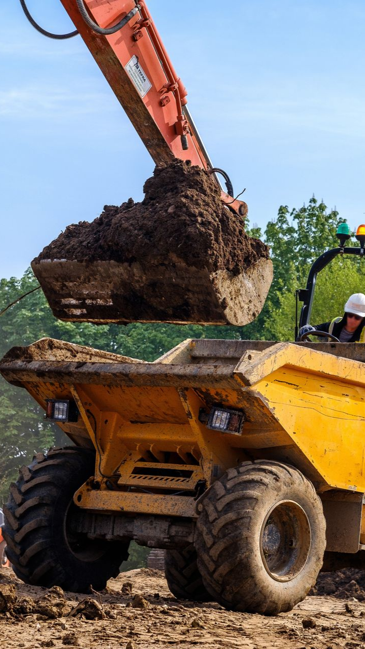 Une excavatrice déverse de la terre dans un dumper jaune 