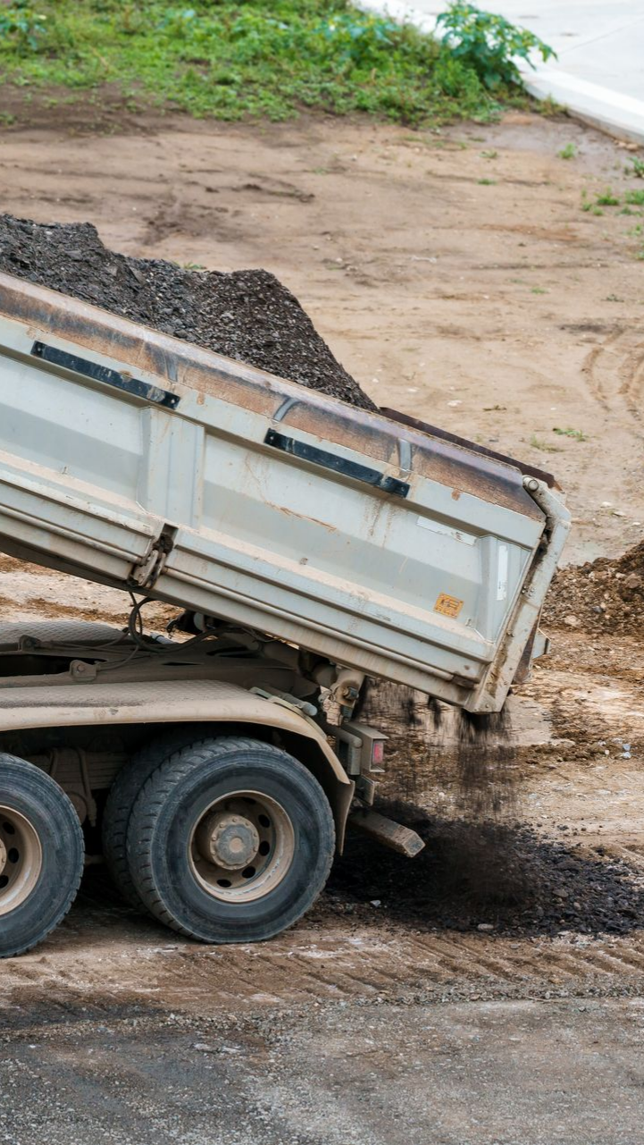 Camion-benne déversant de l'asphalte sur un chantier
