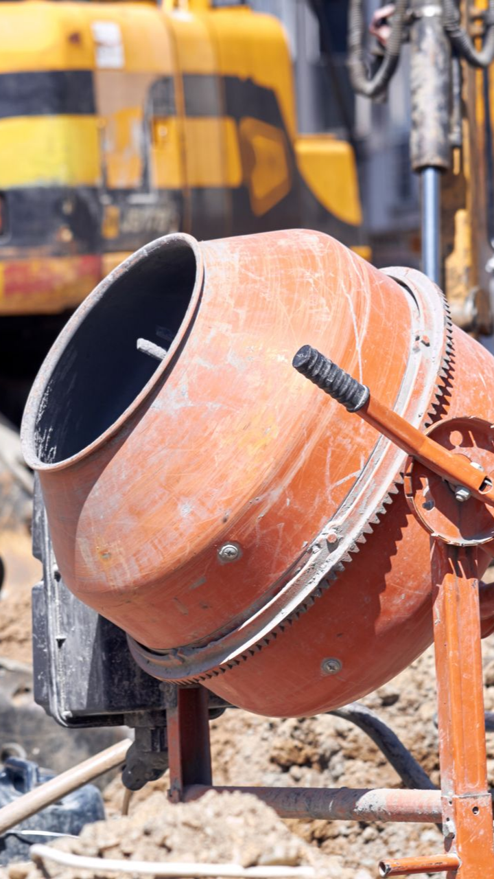 Bétonnière orange sur un chantier, avec poignée et engrenages visibles