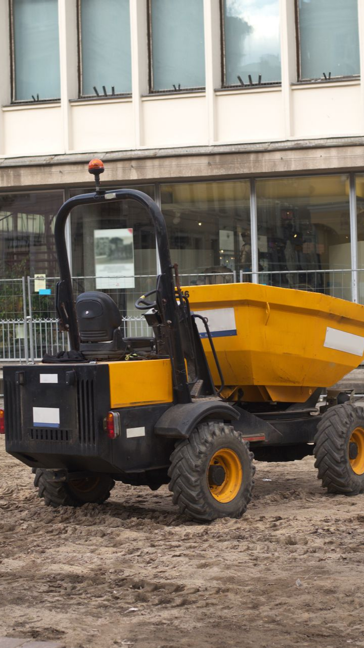Un camion-benne jaune et noir est stationné sur un chantier