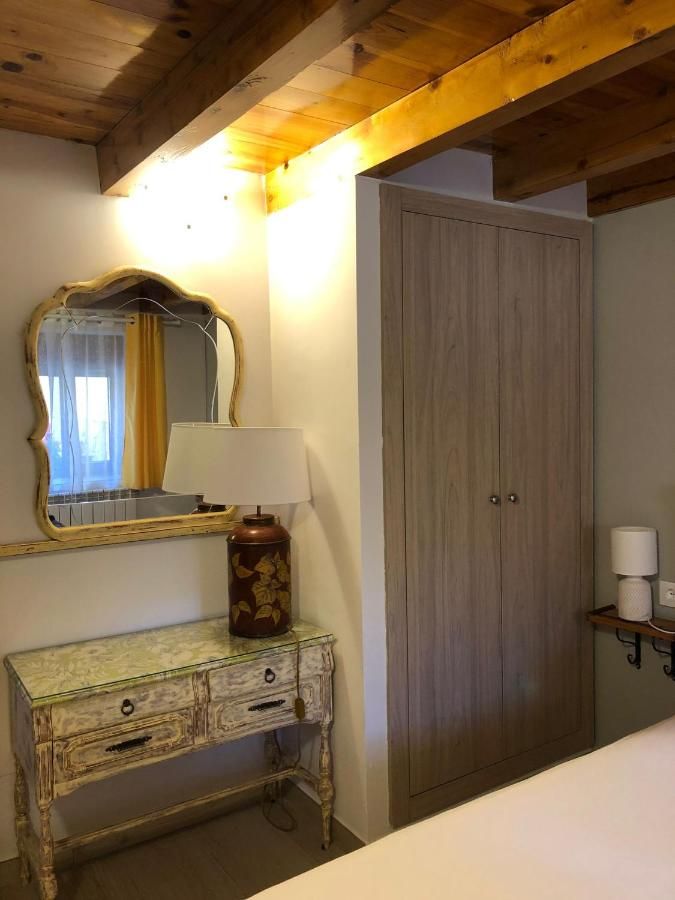 Un dormitorio con mesa, espejo y lámpara.