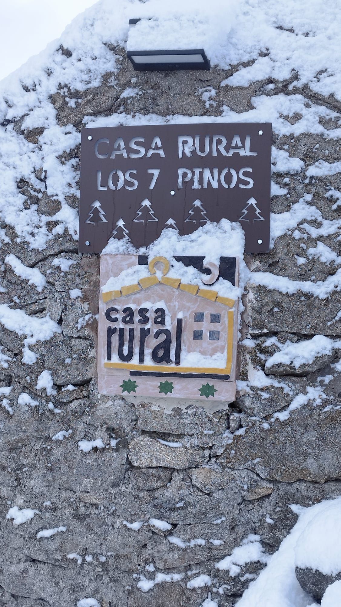 Un cartel en un muro de piedra que dice casa rural los 7 pinos